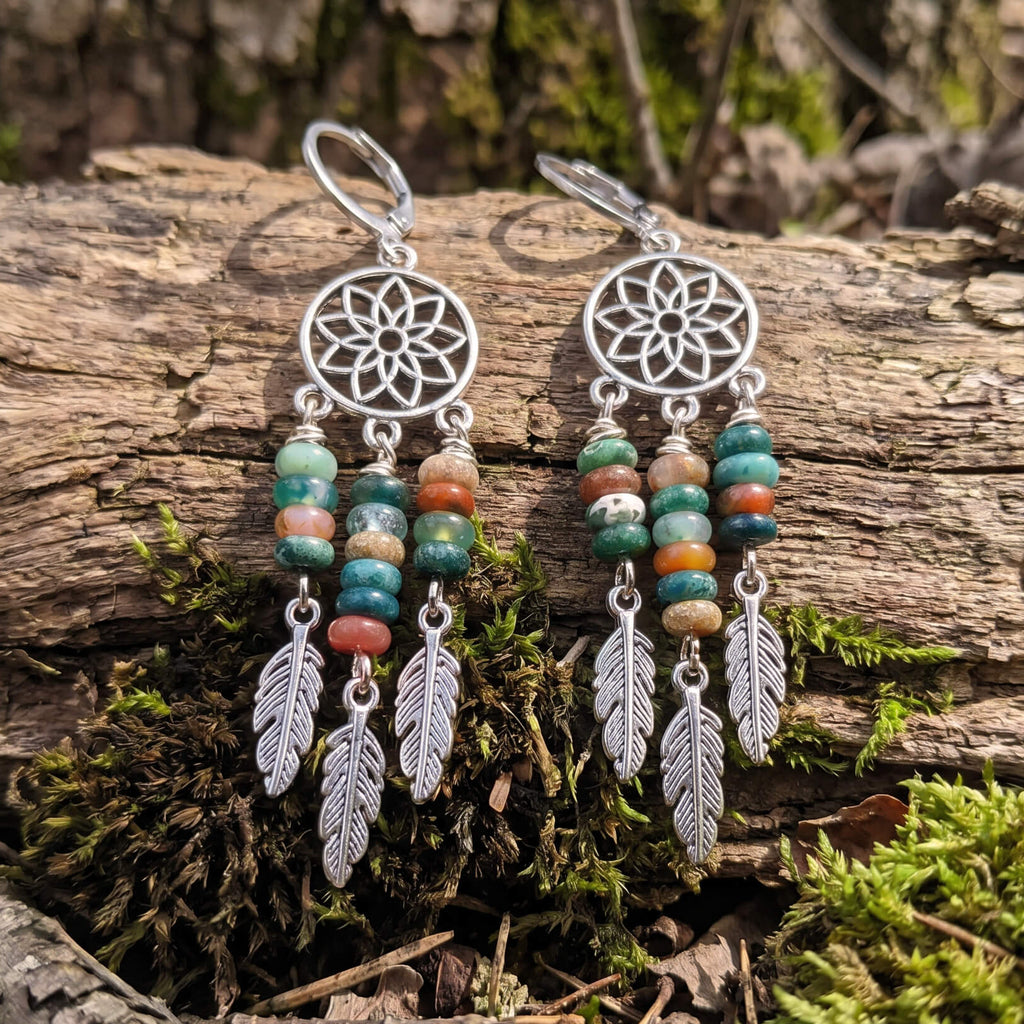 Silver dreamcatcher earrings with fancy jasper beads and feathers on a log